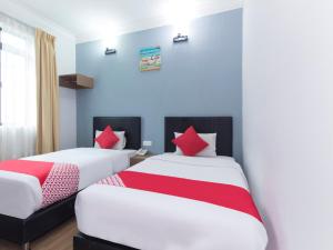 two beds in a room with blue walls and red pillows at CHARISMA HOTEL in Kuantan