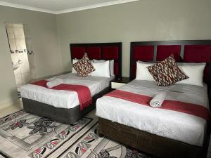 a bedroom with two beds with red headboards at The Hide in Roodepoort in Roodepoort