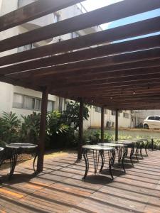 a row of tables and benches under a wooden umbrella at BH PARA 2 - ORLA DA PAMPULHA - Apartamento particular in Belo Horizonte