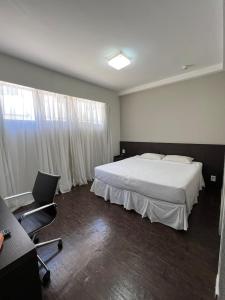 a bedroom with a bed and a desk and a chair at BH PARA 2 - ORLA DA PAMPULHA - Apartamento particular in Belo Horizonte