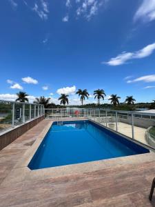 a blue swimming pool with palm trees in the background at BH PARA 2 - ORLA DA PAMPULHA - Apartamento particular in Belo Horizonte