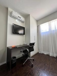 a room with a desk and a chair and a television at BH PARA 2 - ORLA DA PAMPULHA - Apartamento particular in Belo Horizonte
