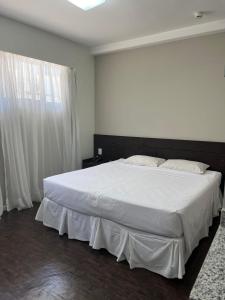 a bedroom with a large white bed and a window at BH PARA 2 - ORLA DA PAMPULHA - Apartamento particular in Belo Horizonte