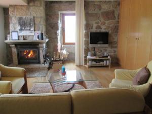 Una sala de estar con un sofá y una chimenea. en Casa da Lage - Piscina privada Sazonal - Vistas rio - Gerês, en Vieira do Minho