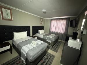 a hotel room with two beds and a television at The Hide in Roodepoort in Roodepoort