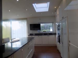 eine Küche mit einer Spüle, einem Kühlschrank und einem Fenster in der Unterkunft Rhiwbina House in Cardiff