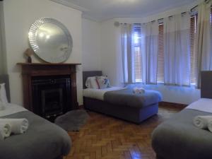1 Schlafzimmer mit 2 Betten, einem Spiegel und einem Kamin in der Unterkunft Rhiwbina House in Cardiff