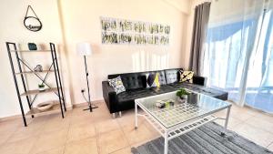 ein Wohnzimmer mit einem schwarzen Sofa und einem Tisch in der Unterkunft Melanos Sea View Apartment in Paphos City