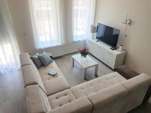 a living room with a couch and a flat screen tv at Silver Lodge Apartment 1 Eger in Eger
