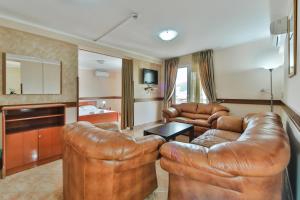 Garni Hotel Koral في بودفا: غرفة معيشة مع كرسيين جلديين وأريكة