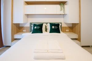 um quarto com uma grande cama branca com almofadas verdes em Smart Concept Living Plaza em Bucareste