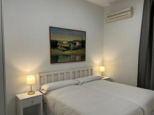 a bedroom with a white bed with two lamps and a painting at Olavide Premium Apartments in Seville