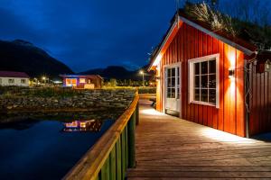a red building with a wooden walkway next to a body of water at Manndalen Sj&oslash;buer in Samuelsberg