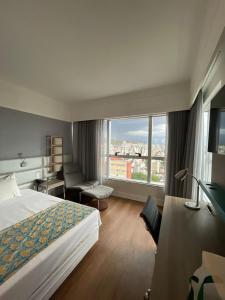 a hotel room with a bed and a large window at BH PARA 2 - HOTEL LUXO Apartamento Particular Savassi in Belo Horizonte