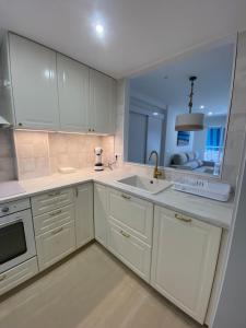 a kitchen with white cabinets and a sink and a window at Arenal Sweet Boutique in Platja de l'Arenal