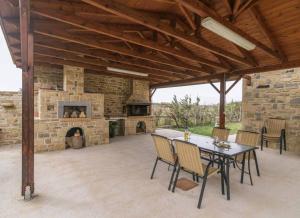 a patio with a stone fireplace and a table and chairs at Villa Beachside in Kamilari