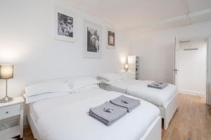 Habitación blanca con 2 camas y espejo. en Soho & Covent Garden Apartment, Sleeps 3, en Londres