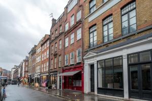 una calle de la ciudad con edificios en un día lluvioso en Soho & Covent Garden Apartment, Sleeps 3, en Londres