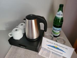 a coffee maker and a bottle on a table at Hotel Am Deich in Norddeich
