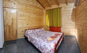 1 dormitorio con 1 cama en una cabaña de madera en Cabaña Itu en Ituzaingó