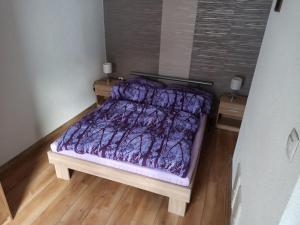 a bed with a purple comforter in a bedroom at Chata Dalma in Vígľaš