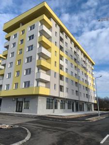 um edifício de apartamentos amarelo e branco com estacionamento em Central Lakeview Apartment, East Sarajevo em Lukavica