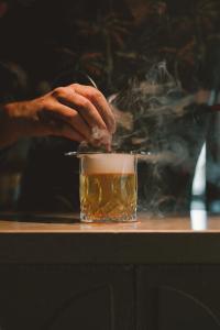 a person stirring a drink in a cup of smoke at Kimpton Aysla Mallorca by IHG in Santa Ponsa