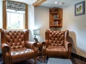 two leather chairs and a desk in a room at Johnsons Cottage - Uk39727 in Taddington