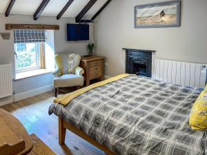 a bedroom with a bed and a chair and a fireplace at Johnsons Cottage - Uk39727 in Taddington