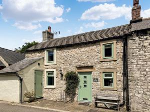 an old stone house with green doors and a bench at Johnsons Cottage - Uk39727 in Taddington