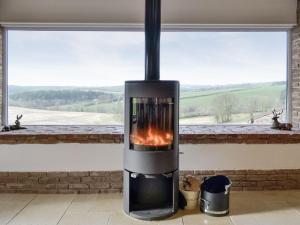 a fireplace in front of a window with a view at Coombe View in South Redworthy