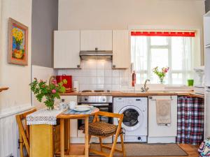a kitchen with a table and a washing machine at Kirk Wynd Cottage in Kirriemuir