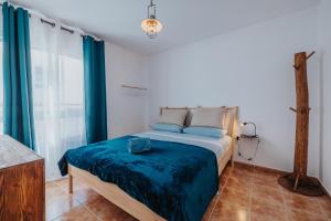 1 dormitorio con 1 cama con sábanas azules y cortinas azules en Casa Allegranza, en Cotillo