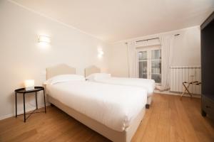 two beds in a white bedroom with a window at Santantonio Suite, Porta Susa in Turin