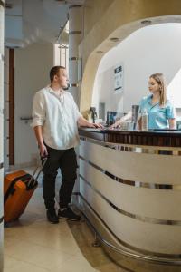 Garni Hotel Koral في بودفا: رجل مع حقيبة تقف في مكتب مع امرأة