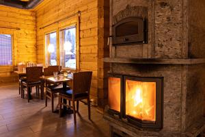 a dining room with a fireplace with a table and a tv at Arctic River Resort in Ivalo