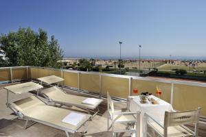 a balcony with tables and chairs and a view of the ocean at Hotel Excelsior in Bibione