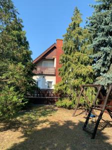 a house in the background with trees and a swing at Attila Vendégház in Kiskunmajsa