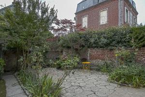 a garden with a brick building and a yellow chair at Maison de ville avec jardin Etretat in Étretat
