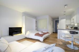 ein weißes Schlafzimmer mit einem Bett und einer Küche in der Unterkunft Charmant Studio proche de la Toison d'Or in Brüssel