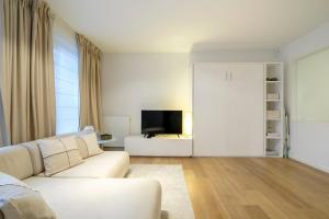 ein Wohnzimmer mit einem weißen Sofa und einem TV in der Unterkunft Charmant Studio proche de la Toison d'Or in Brüssel