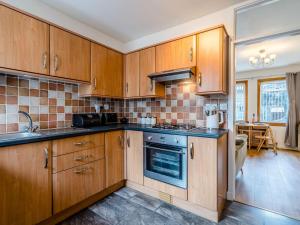 a kitchen with wooden cabinets and a stove top oven at Chilmello Cottage in Pittenweem