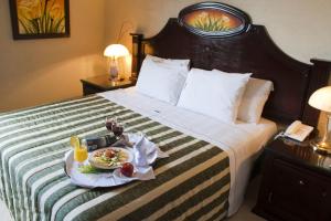 a hotel room with a bed with a tray of food on it at Hotel Casino Plaza in Guadalajara