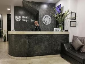 Um homem a falar ao telefone atrás de um balcão na entrada. em Hotel Radel Bogotá em Bogotá