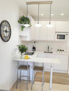 a kitchen with white cabinets and a counter with stools at M&D Centro Málaga in Málaga