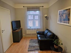 een woonkamer met een zwarte leren bank en een televisie bij Artilerija's apartment in Rīga