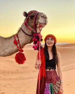 a woman standing next to a camel in the desert at Authentic Desert Luxury Camp in Merzouga