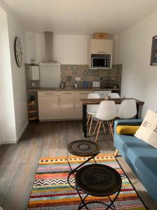 sala de estar con sofá azul y cocina en Adorable Guest House « bienvenue chez vous ! » en Bordères-sur-lʼÉchez