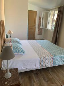 um quarto com uma cama e uma mesa com um candeeiro em Adorable Guest House « bienvenue chez vous ! » em Bordères-sur-lʼÉchez