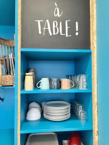 a blue shelf with plates and a table sign on it at Kyriad Direct Dijon Sud - Chenove in Chenôve